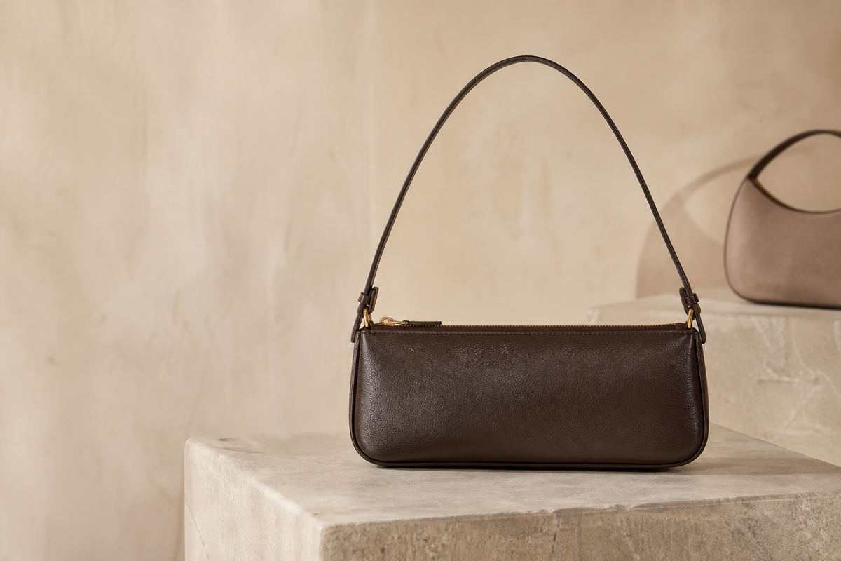 Unbranded espresso leather east-west shoulder bag on a stone pedestal