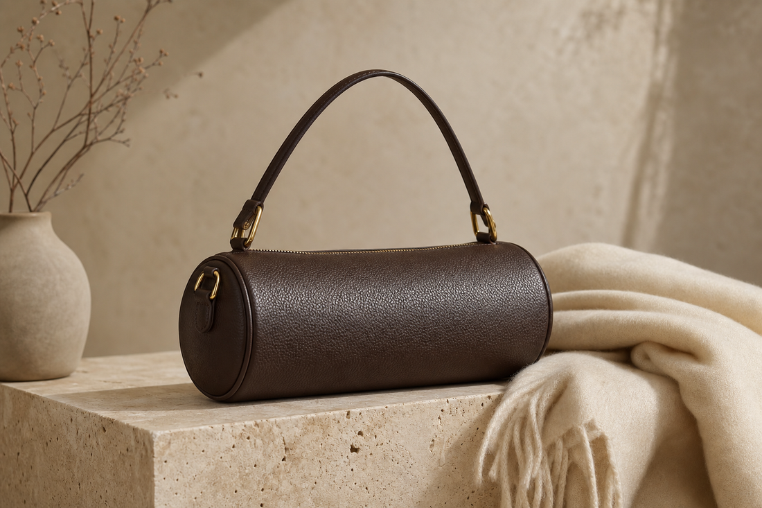 Unbranded espresso leather barrel bag in a refined neutral editorial setting
