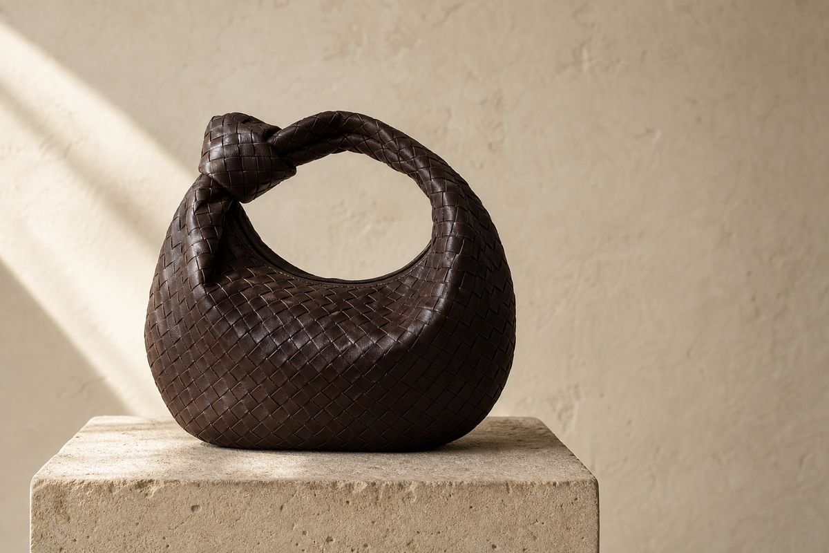 Unbranded espresso woven leather knot-handle handbag on a stone pedestal